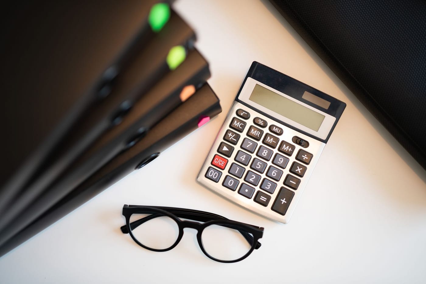 A clean desk with a calculator, reading glasses and file folders