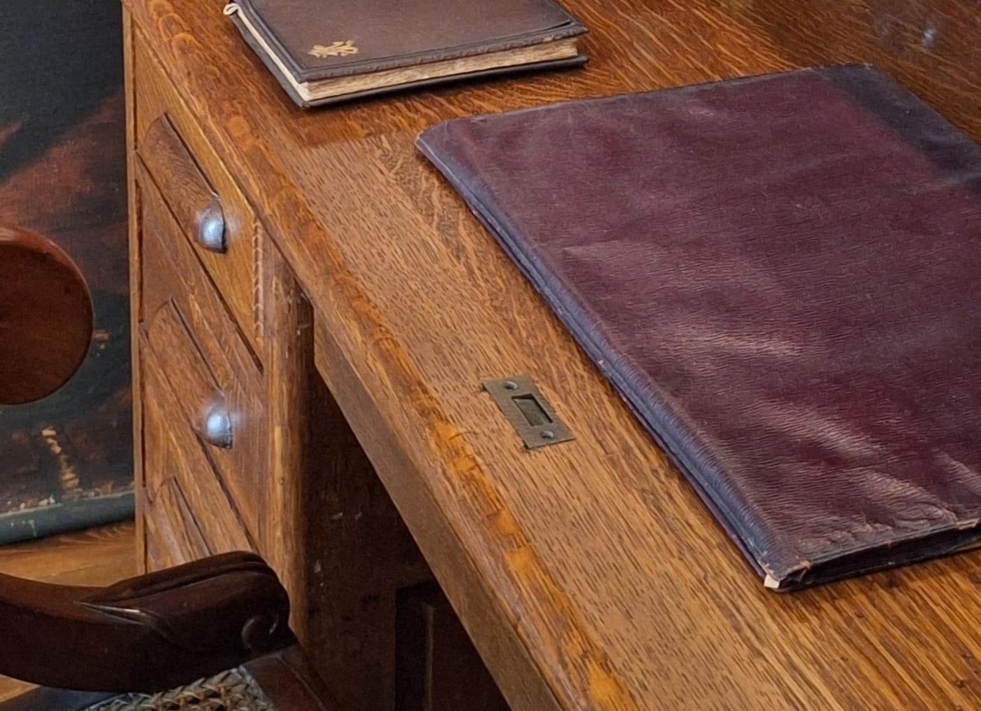An oak advocate's desk with a leather folder and a bound volume